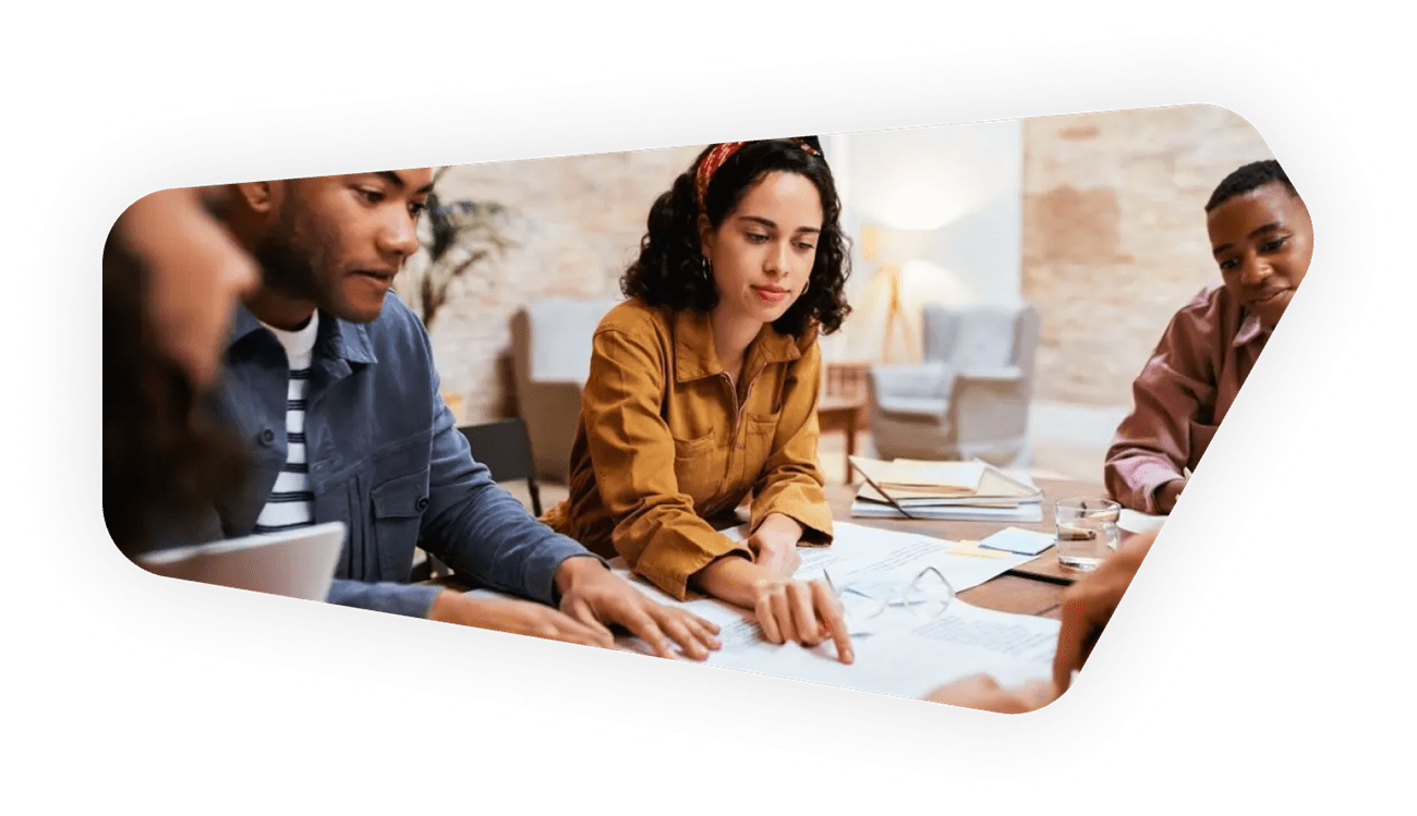 A group of people gathered around a table covered with papers, collaborating and discussing ideas in a team setting.