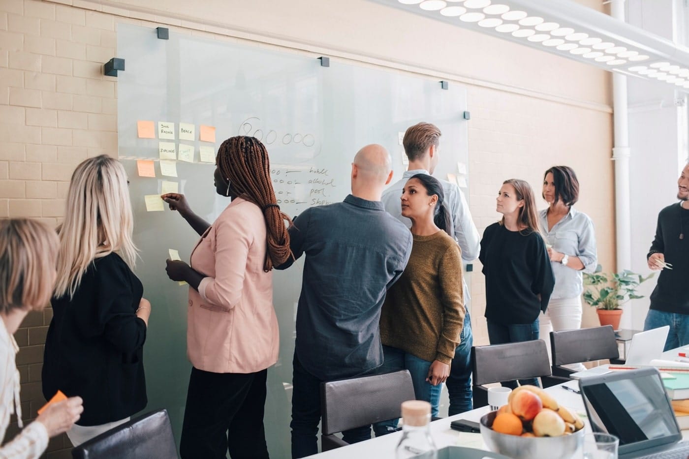 A team gathered around a whiteboard filled with notes and diagrams, collaborating and discussing ideas during a brainstorming session.